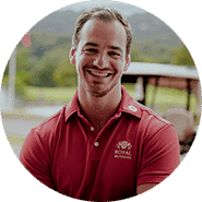 Souriante, en polo rouge "Royal", devant verdure et golf.
