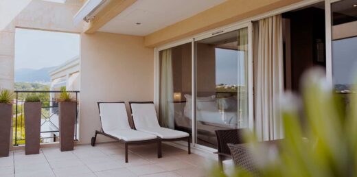 Balcon moderne, chaises blanches, vue verdoyante.