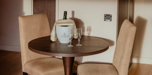 Table en bois, deux chaises, champagne dans une pièce bien éclairée.