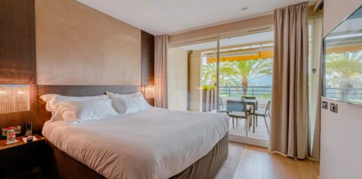 Lit bien fait dans une chambre moderne avec balcon et palmiers.