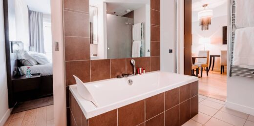 Une salle de bains moderne avec baignoire, carrelage et vue naturelle sur la chambre et la salle à manger.