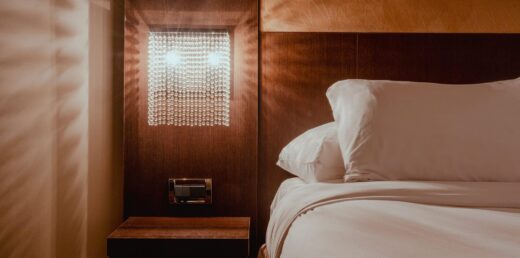 Chambre moderne : applique cristal, tête lit bois, literie blanche.