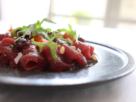 Carpaccio orné de roquette, légumes et pignons.